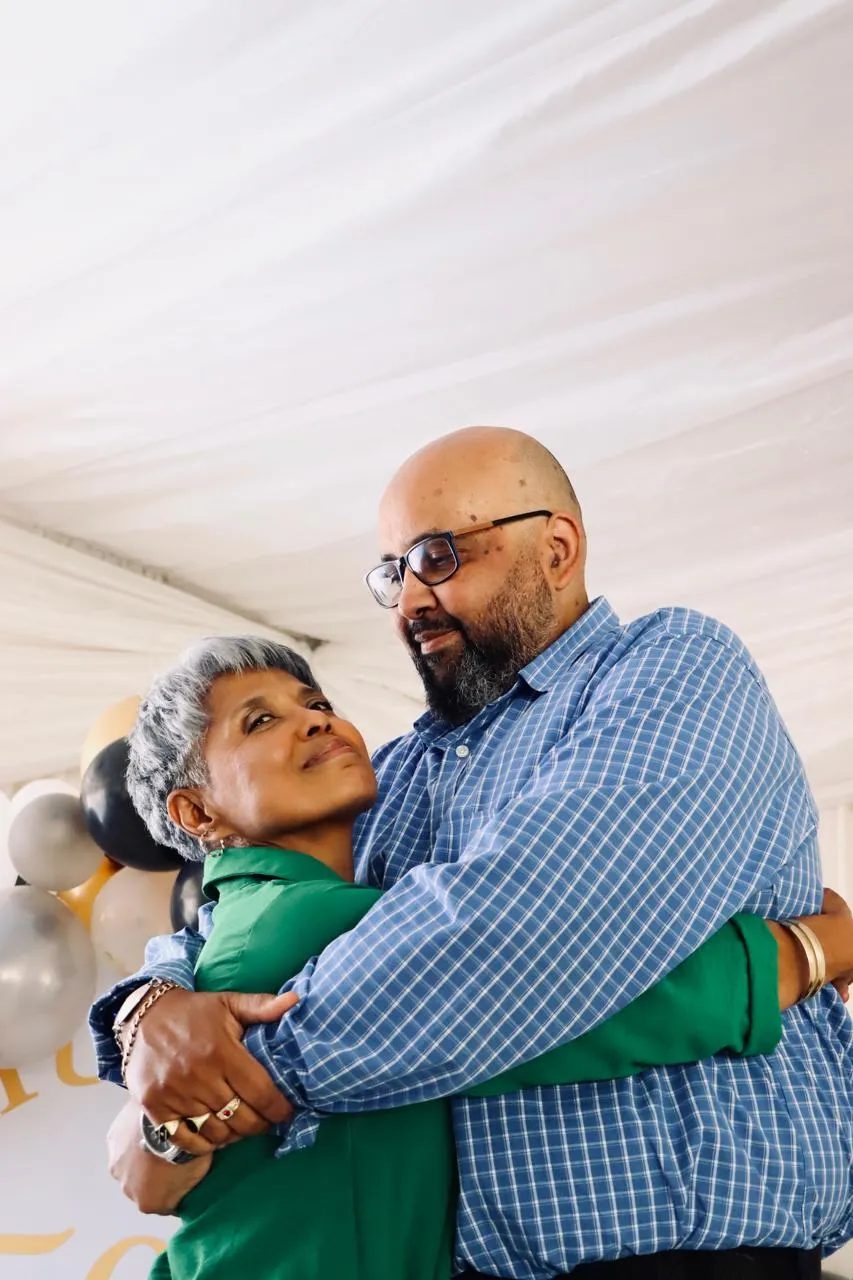 A man in a checked shirt hugging an older woman in green