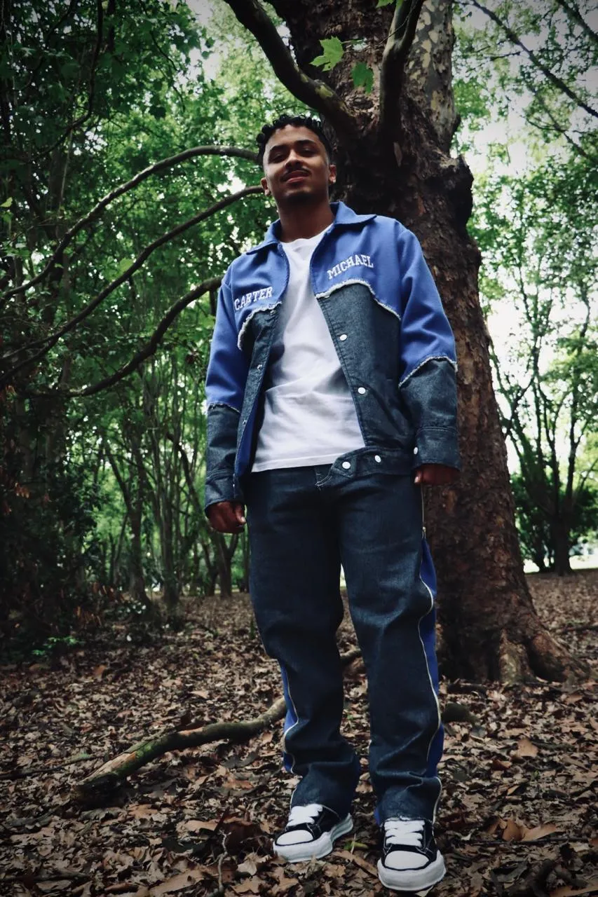 Full-length shot of a man in a Carter Michael denim jacket standing under a large tree