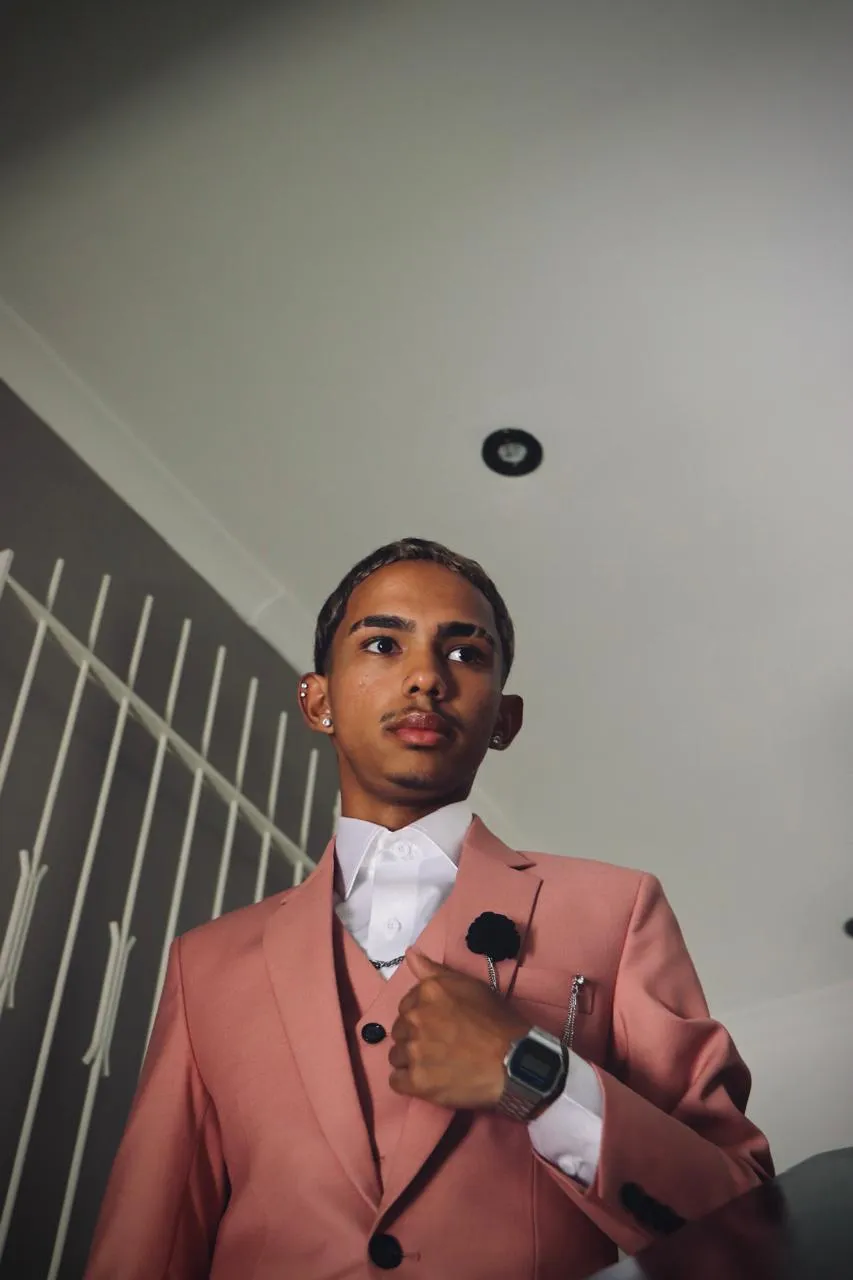 A young man in a salmon suit and waistcoat, photographed from below