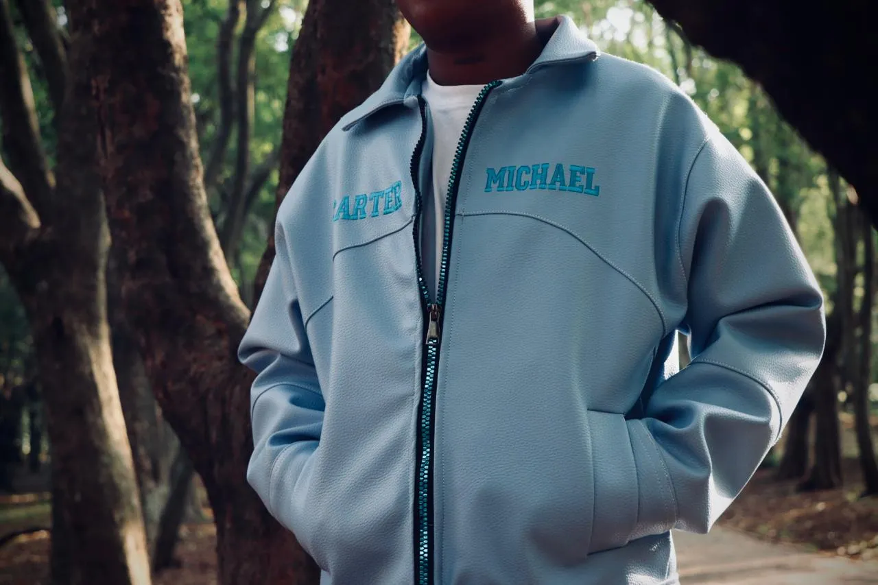 Close crop of the pale blue Carter Michael track jacket with its embroidered lettering